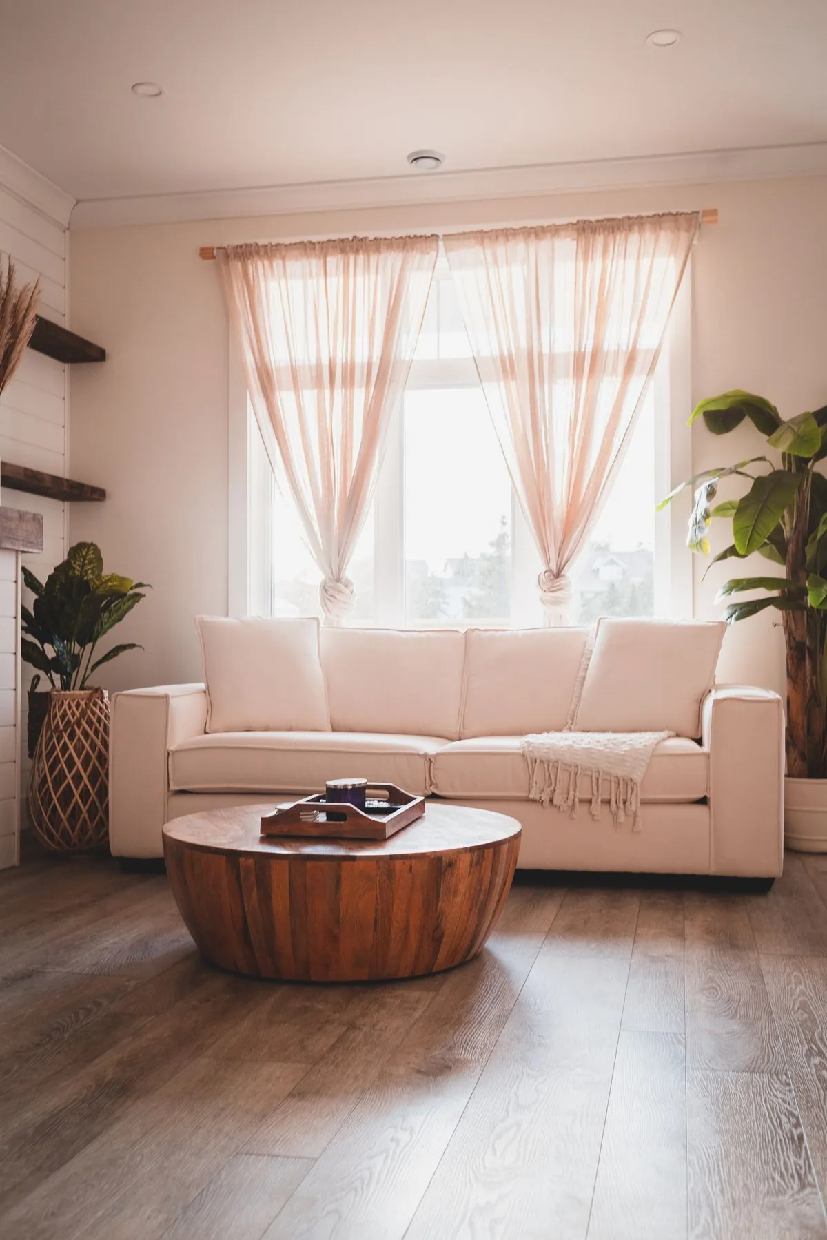 Helles Wohnzimmer mit Sofa, Holztisch und Pflanzen am Fenster