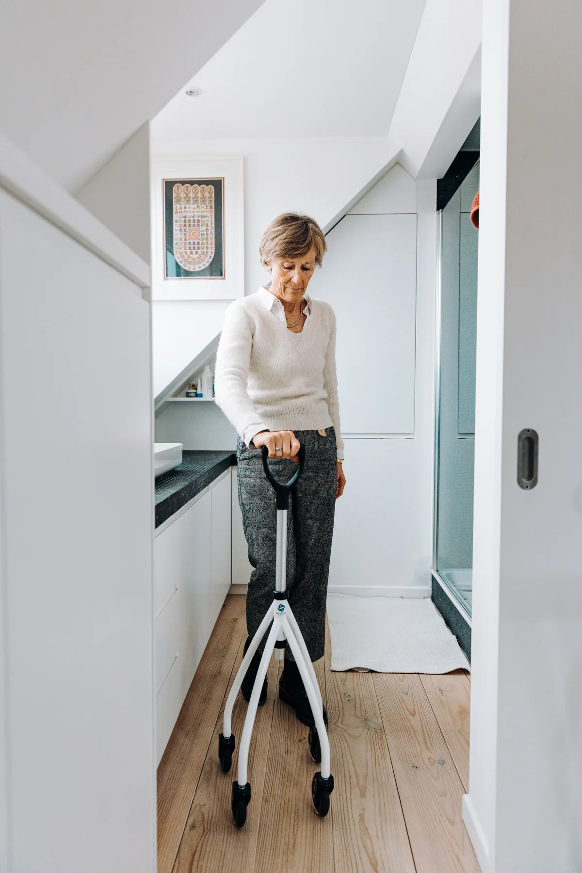 Ältere Frau bewegt sich mit einem Rollator durch eine helle Wohnung